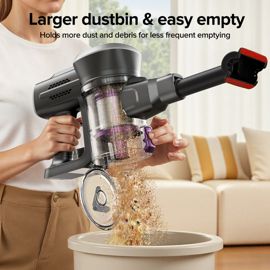 Person using a handheld vacuum cleaner to empty debris into a trash bin in a living room.