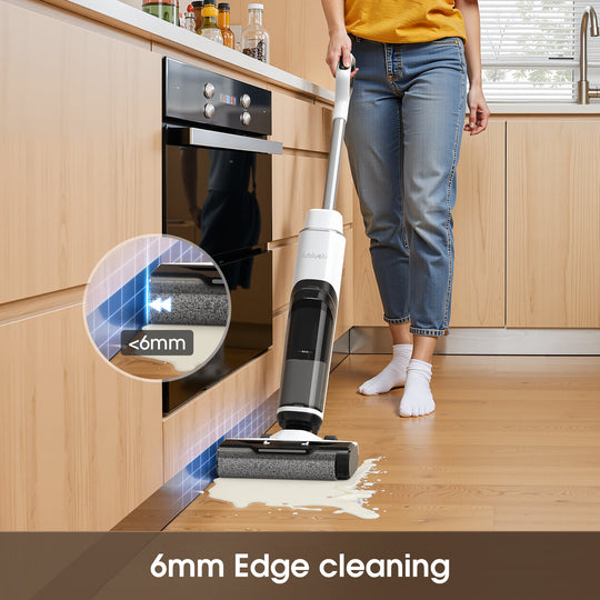 Person using a cleaning device to clean a kitchen floor with a focus on edge cleaning.